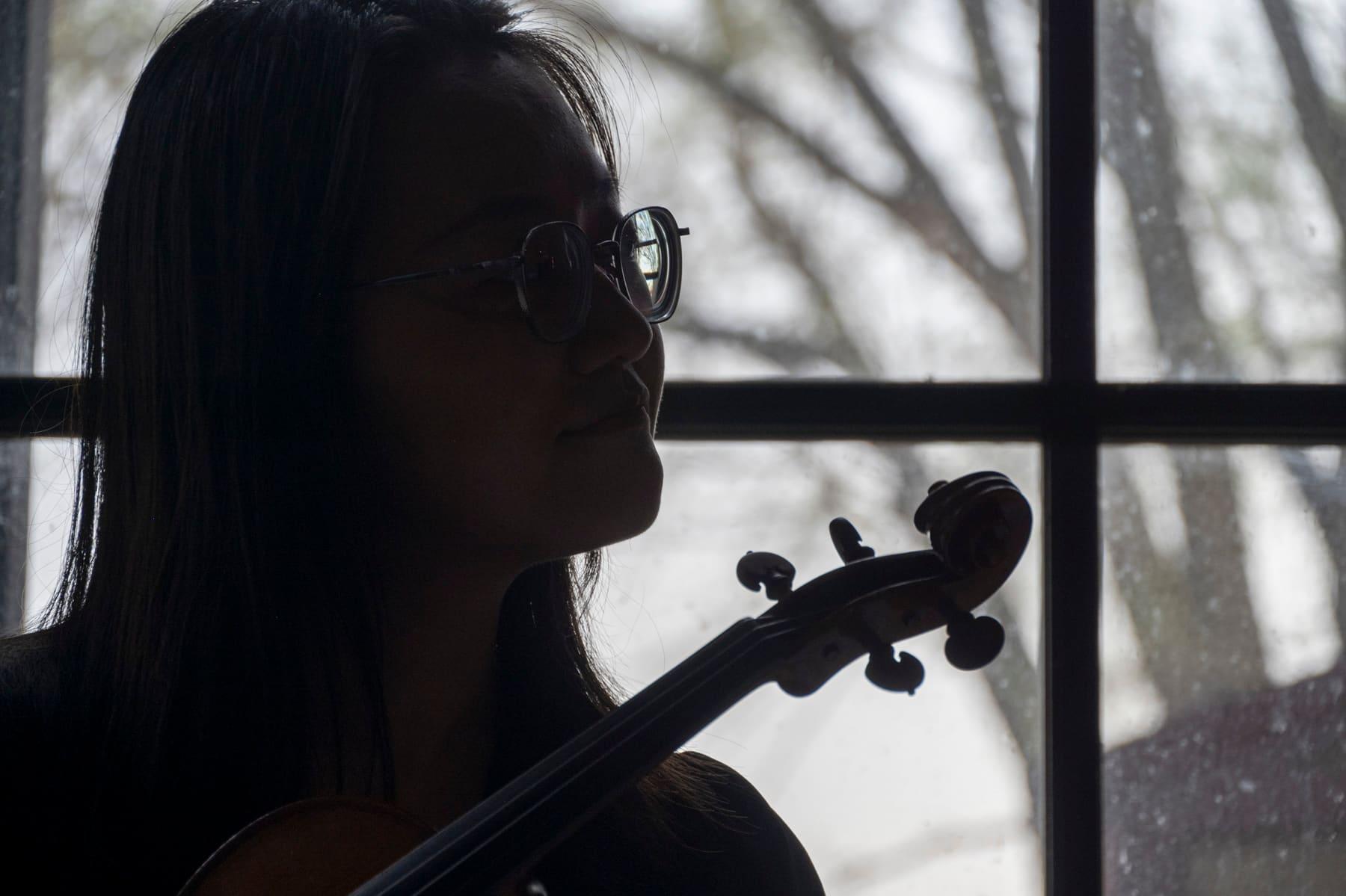 Violinist silhouetted against a window during a musical performance
