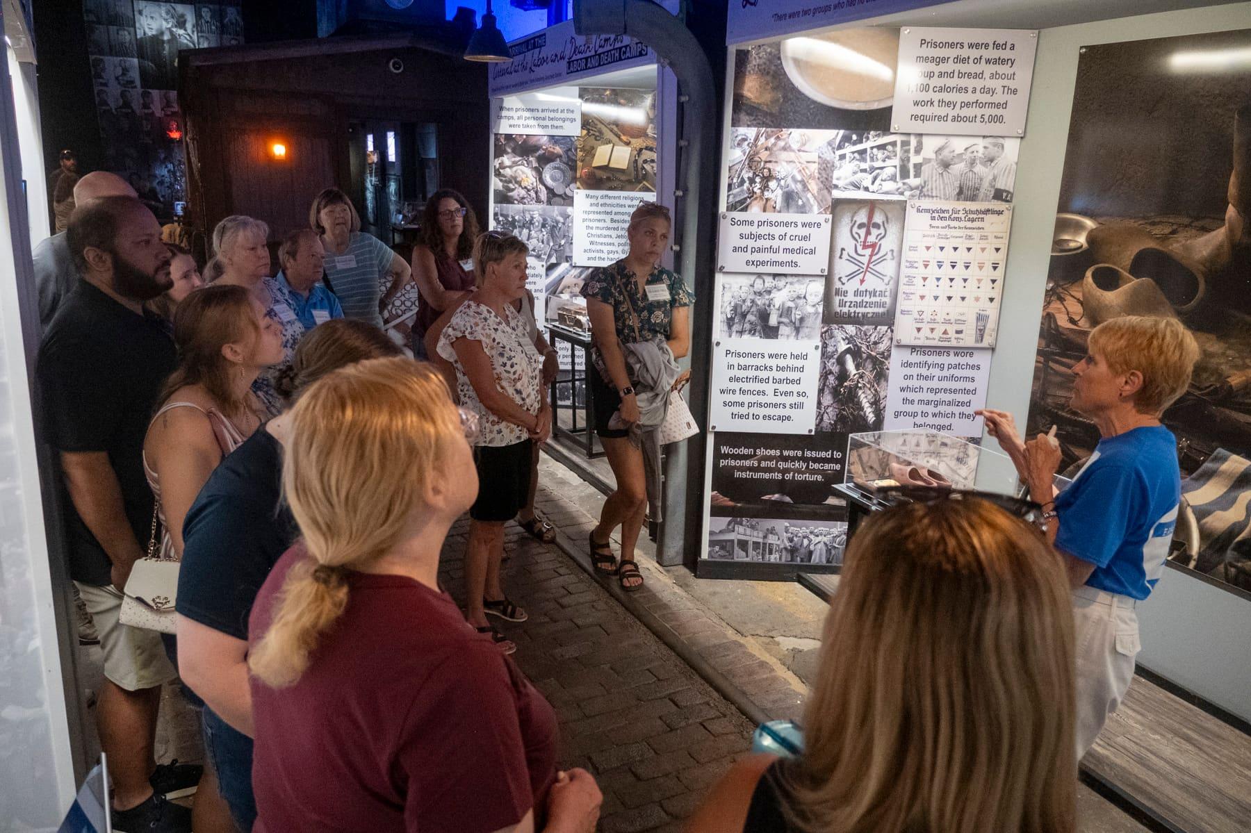 A group listening to a guide beside Holocaust history panels