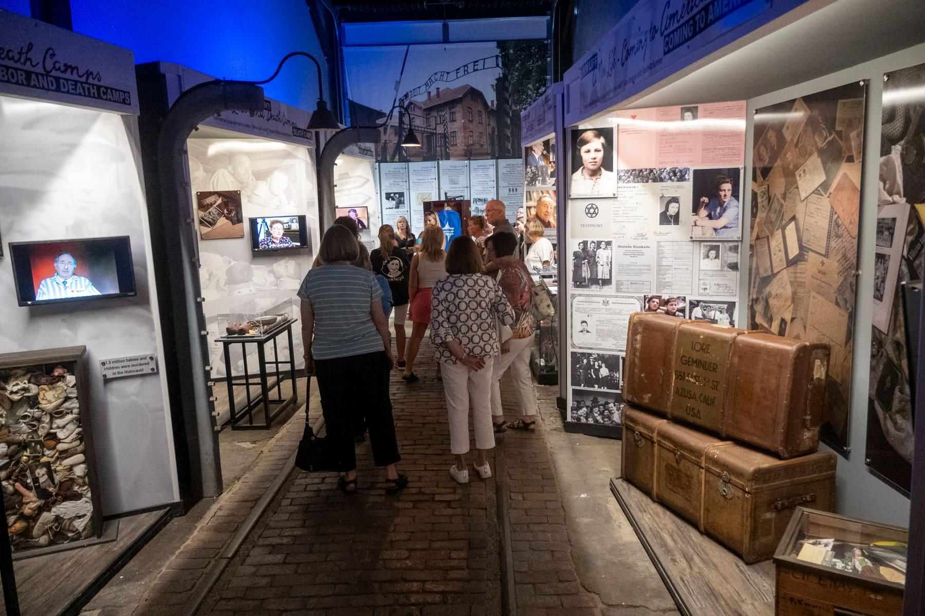 Visitors walking between illuminated Holocaust history displays