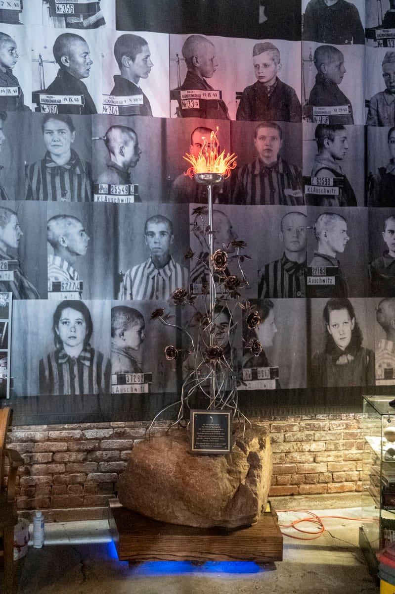 Memorial candle glowing before a wall of historic portraits