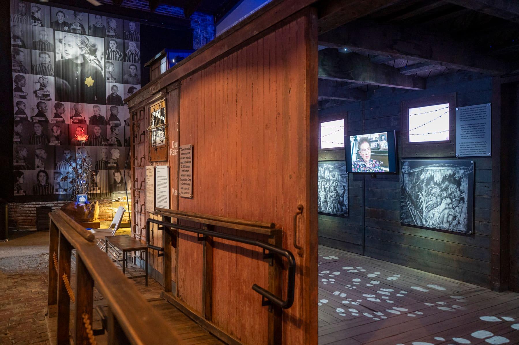 Accessible ramp beside a wooden railcar and historic portrait wall