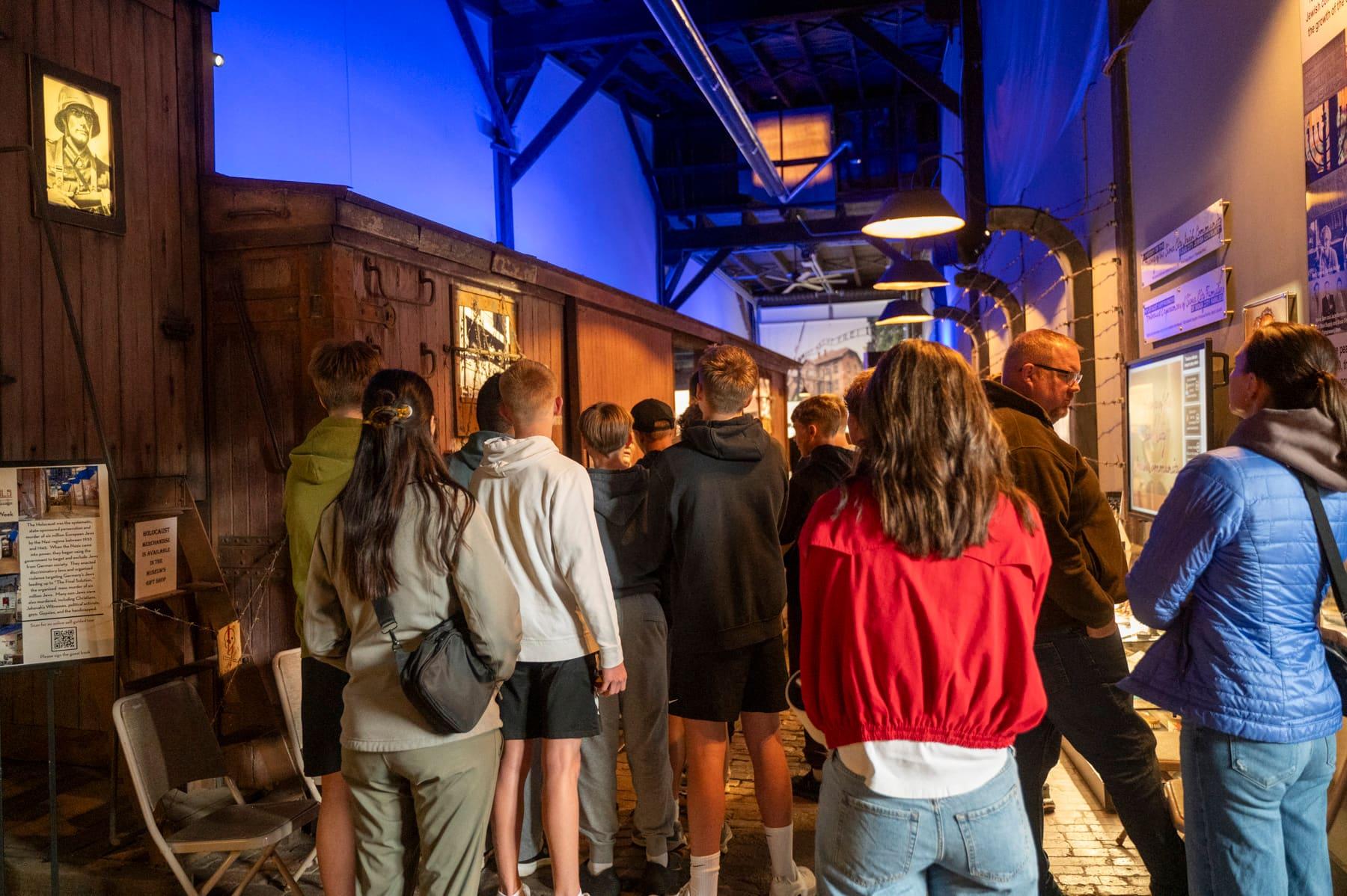 Visitors gathered along the walkway beside a wooden railcar