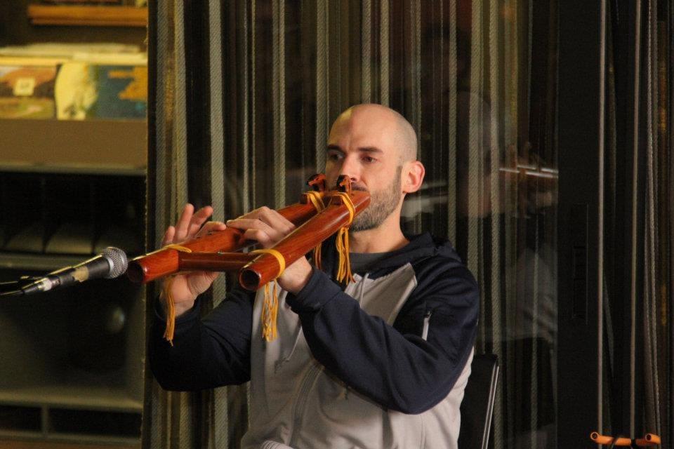 An adult plays violin into a microphone on a small stage.