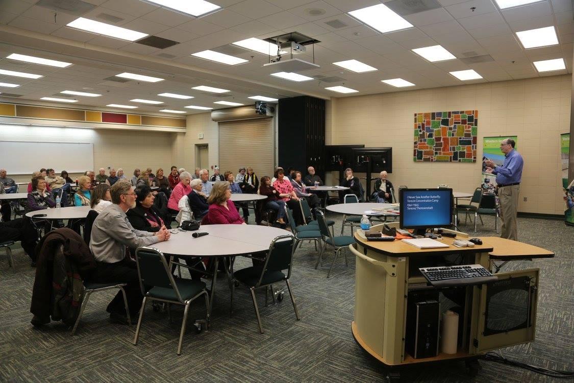 Adults sit at round tables during a classroom presentation.