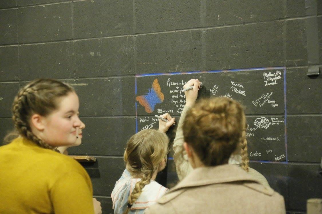 Visitors write messages on a large chalkboard mural.