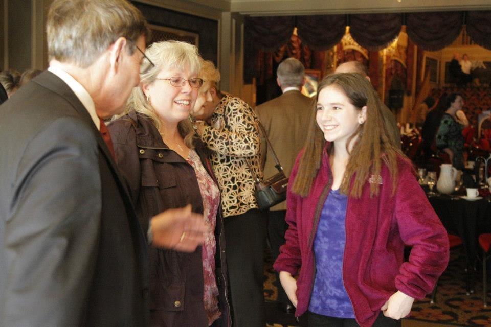 An adult talks with two adults at an indoor reception.