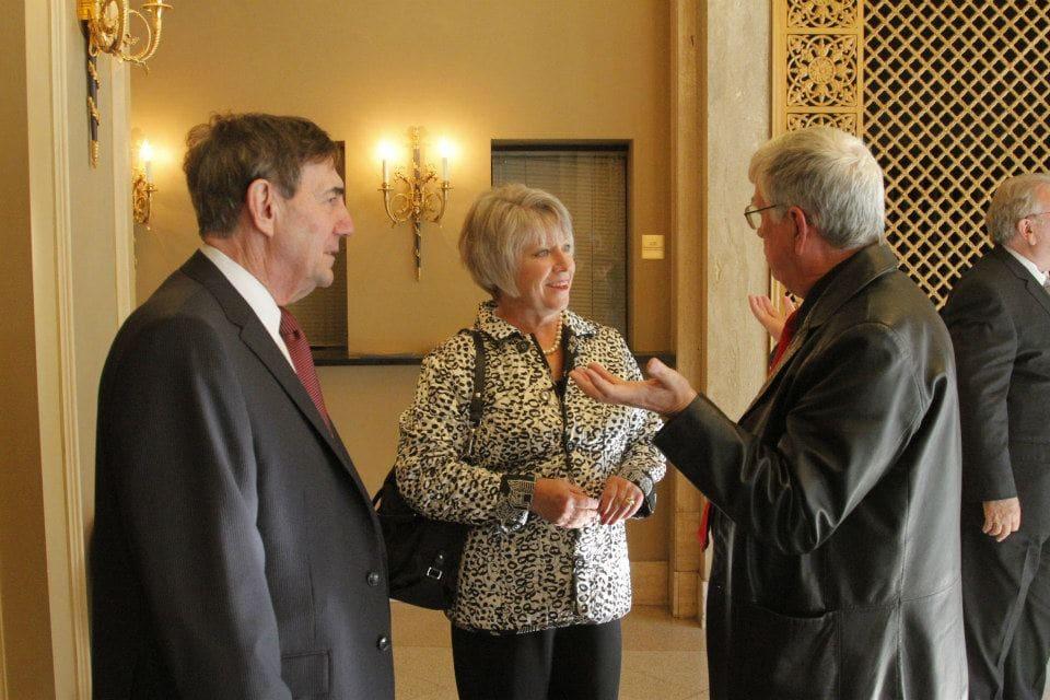 Three adults converse in an ornate lobby.