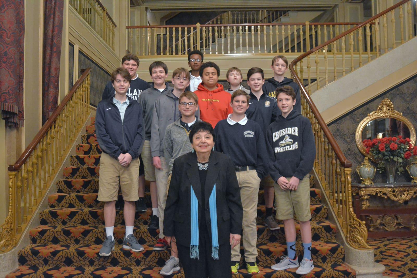 Students pose together on an ornate staircase.