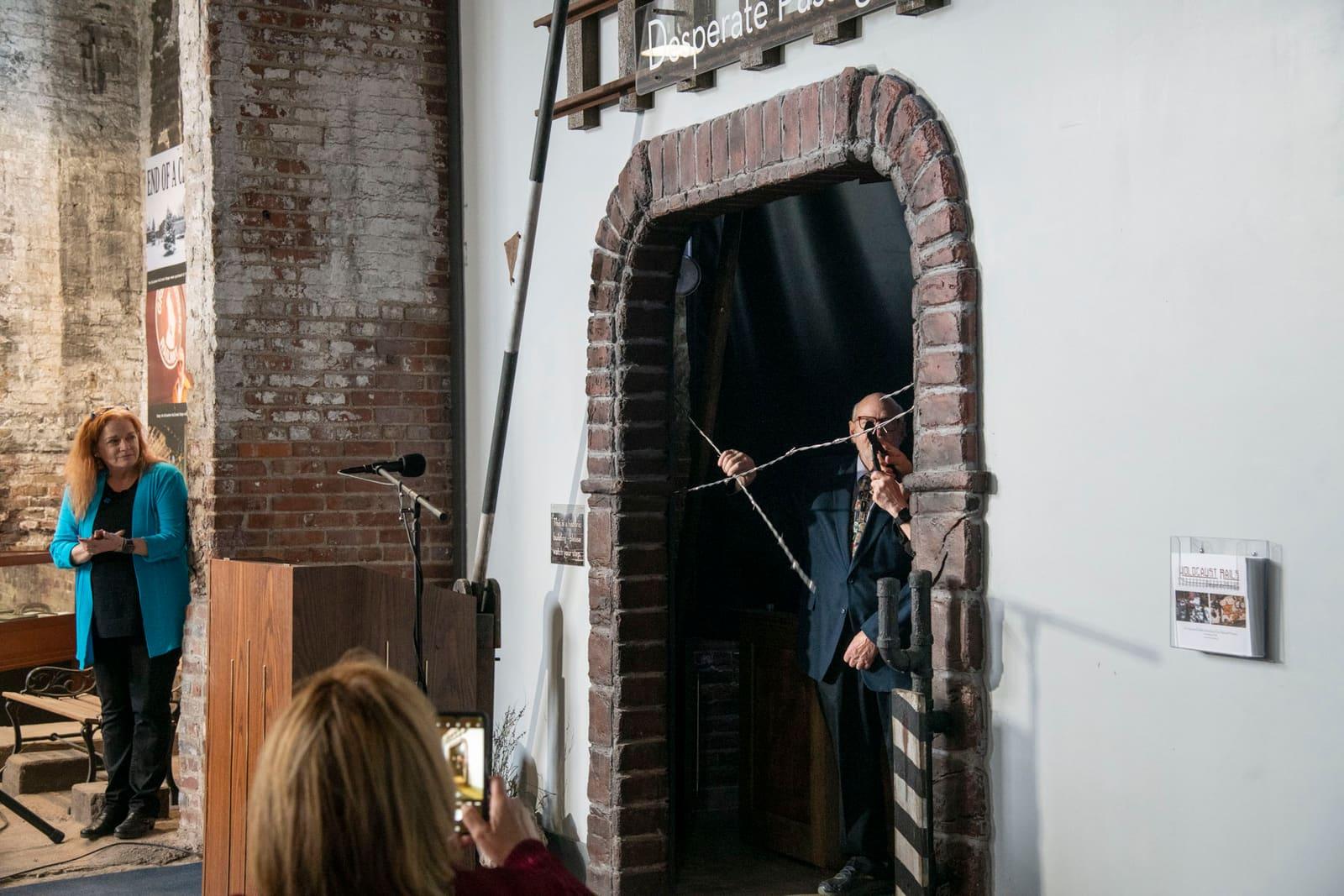 An adult speaks near a large brick archway.