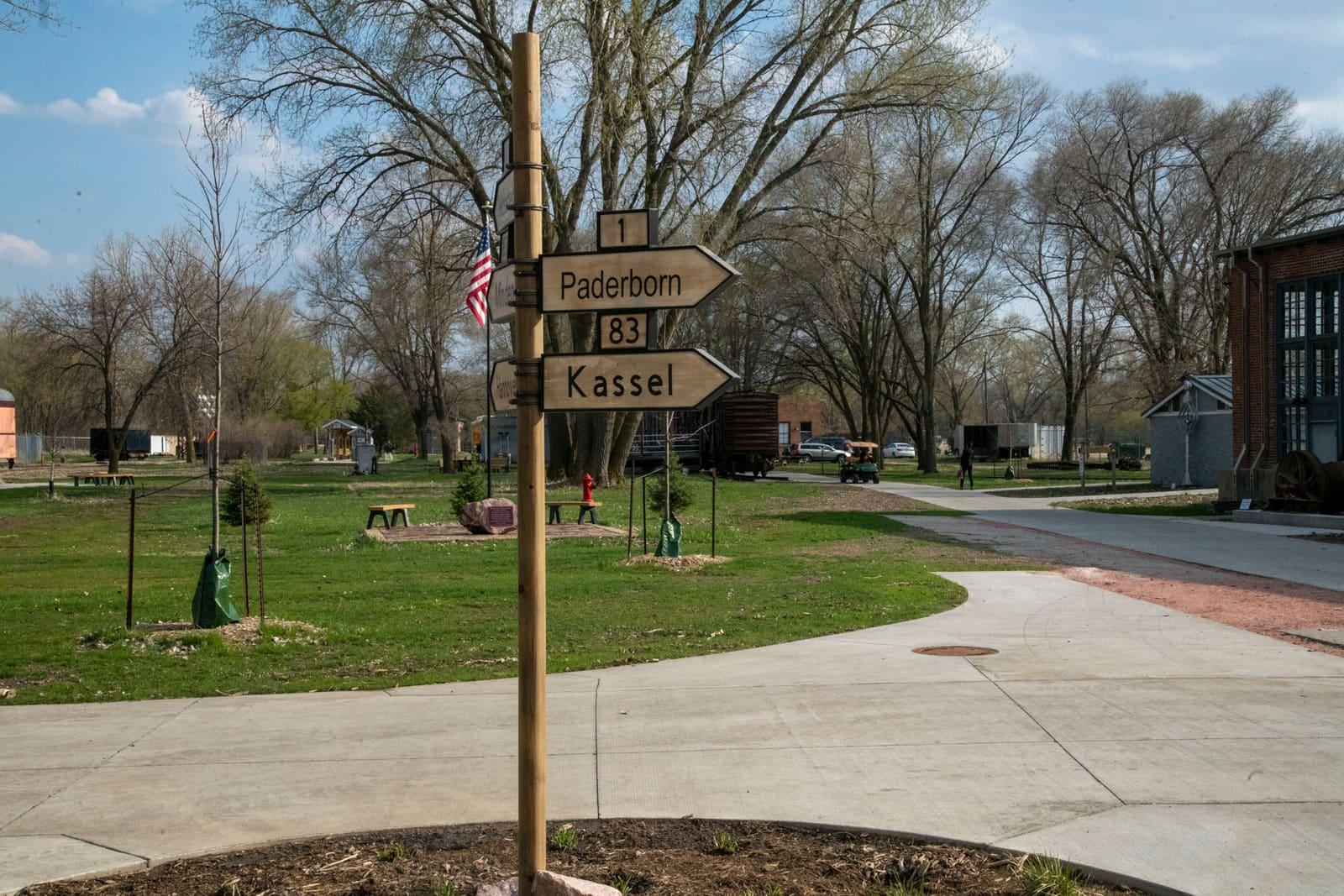 A signpost stands beside paths in a grassy park.