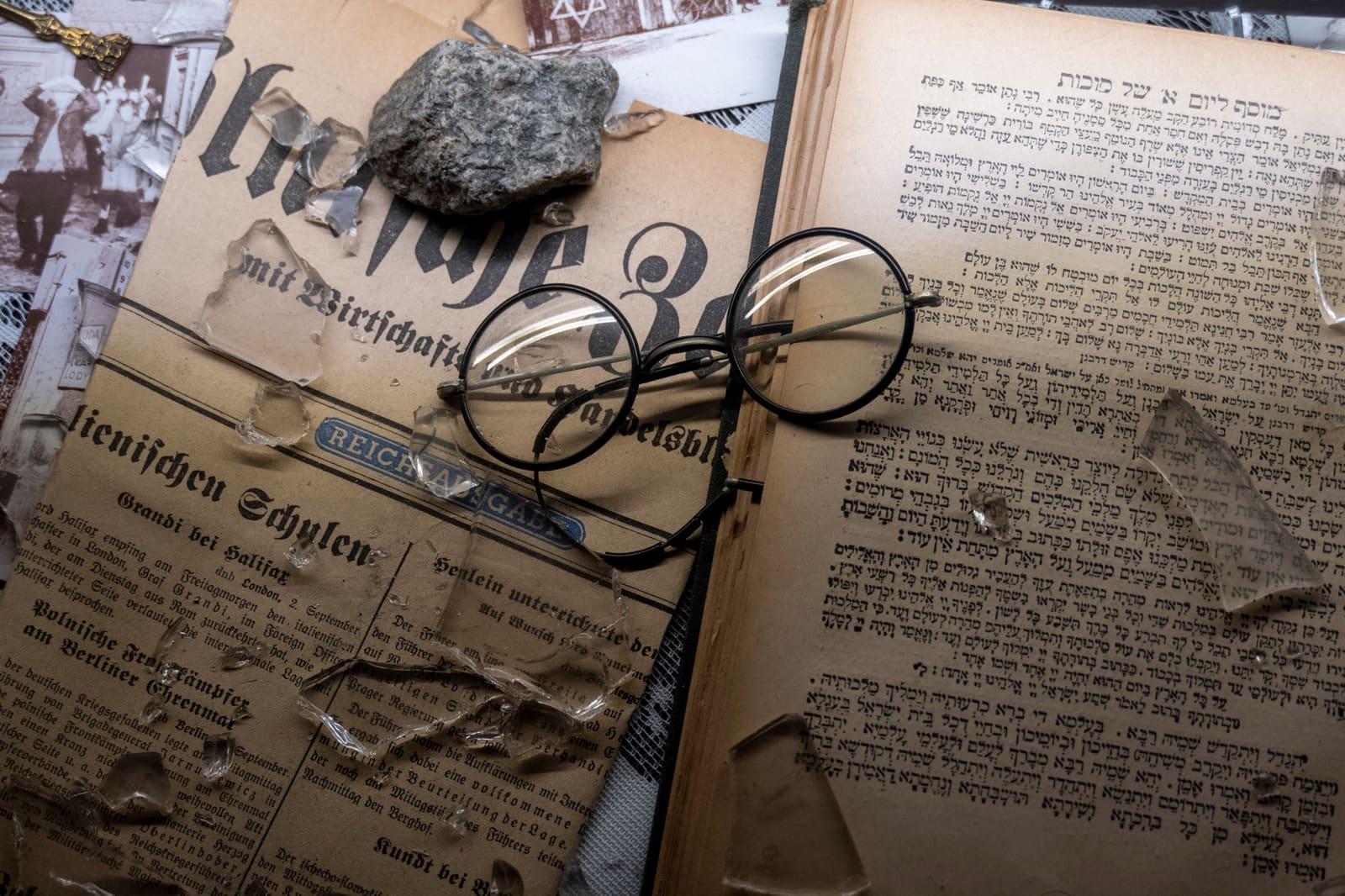 Eyeglasses rest on historical documents beside a small cloth bundle.