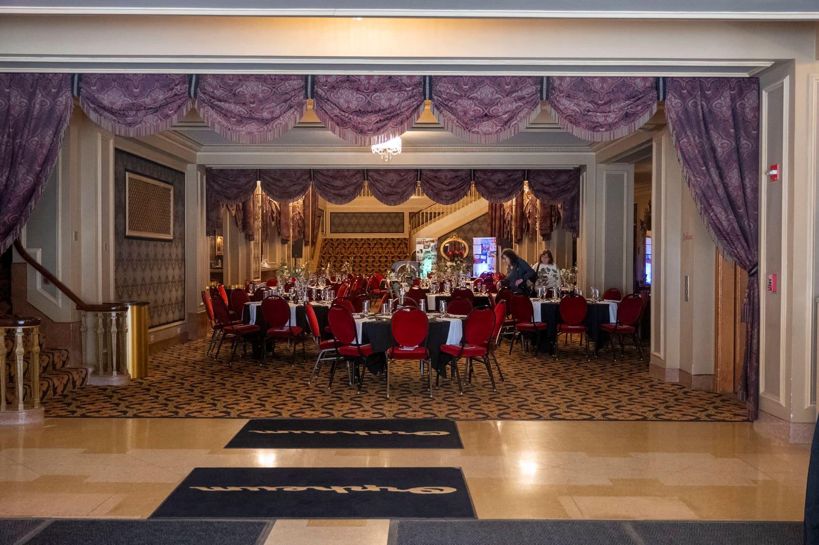 A lobby doorway frames banquet guests seated in an ornate room.