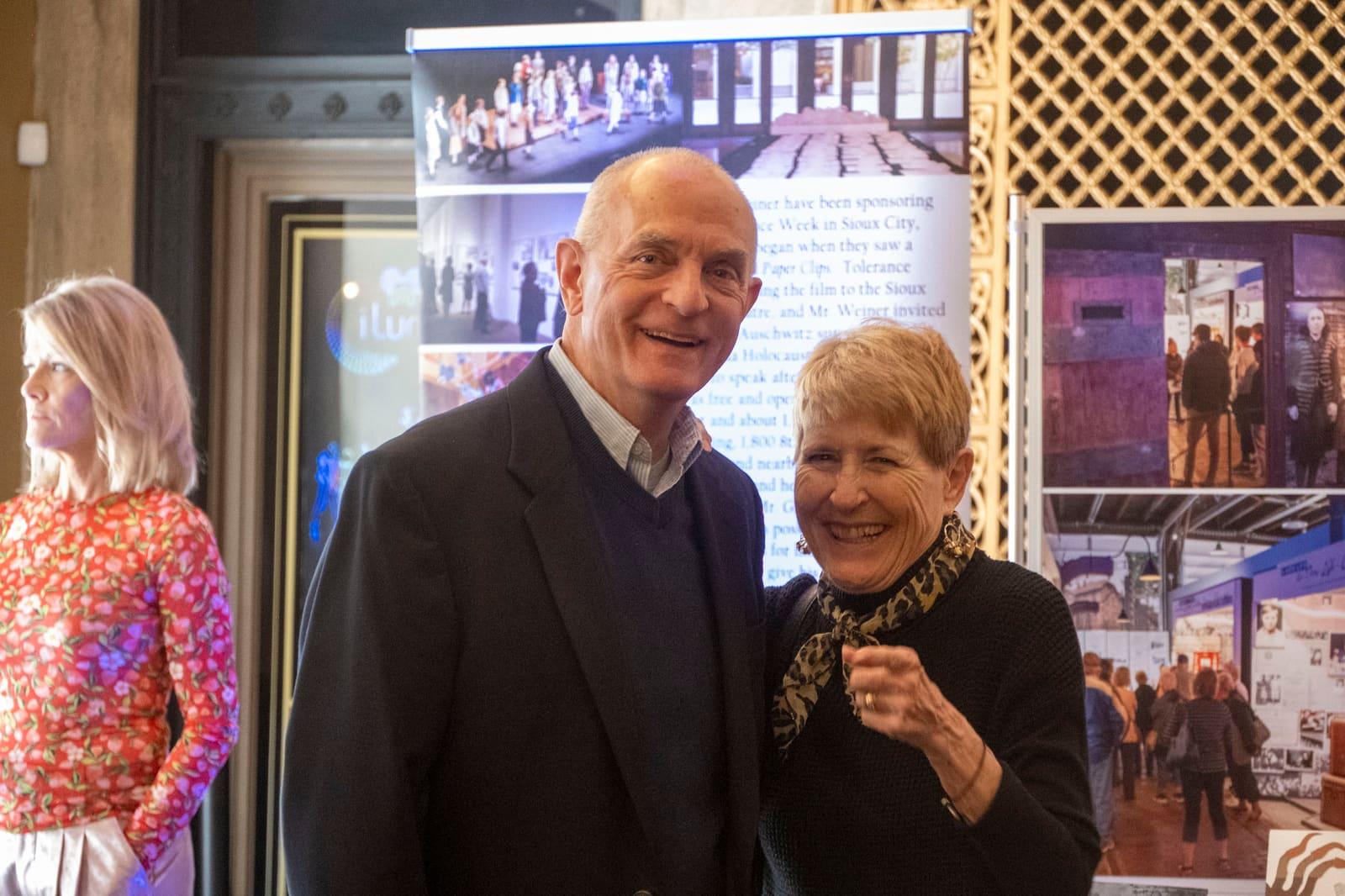 Two smiling adults pose beside an exhibit banner.