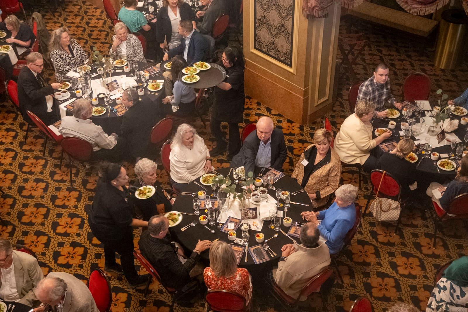 An overhead view shows guests seated around banquet tables.