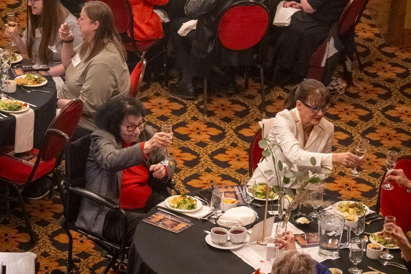 People greet one another between banquet tables.