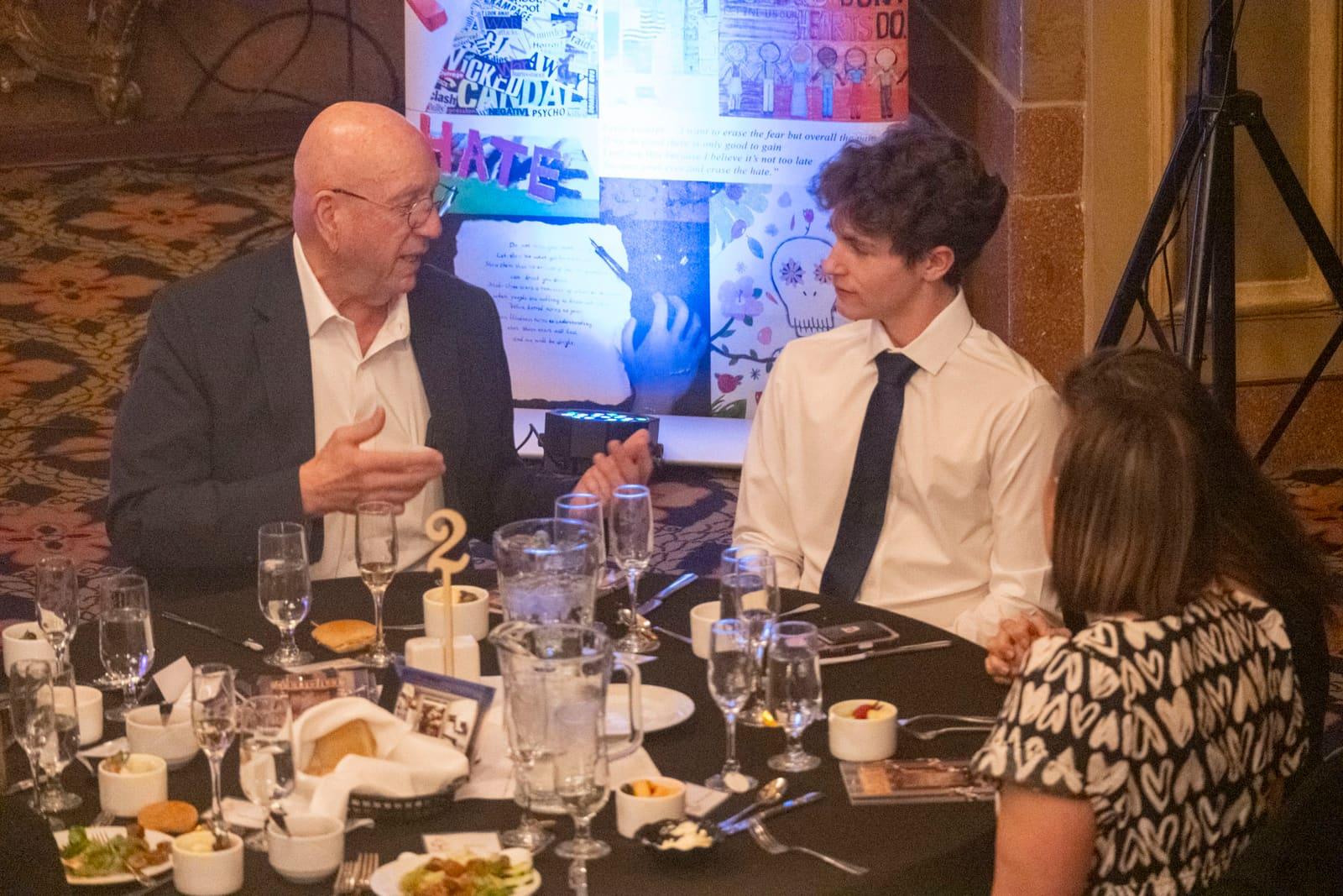 Two adults converse at a banquet table.
