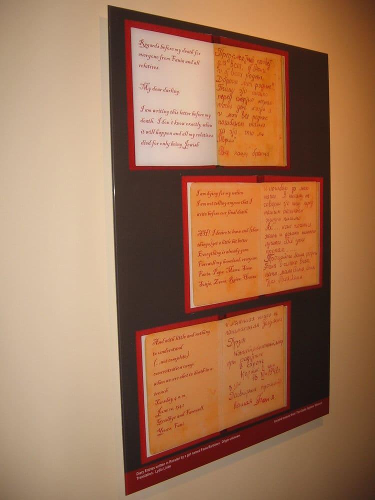 Three framed handwritten pages hang vertically on a gallery wall.