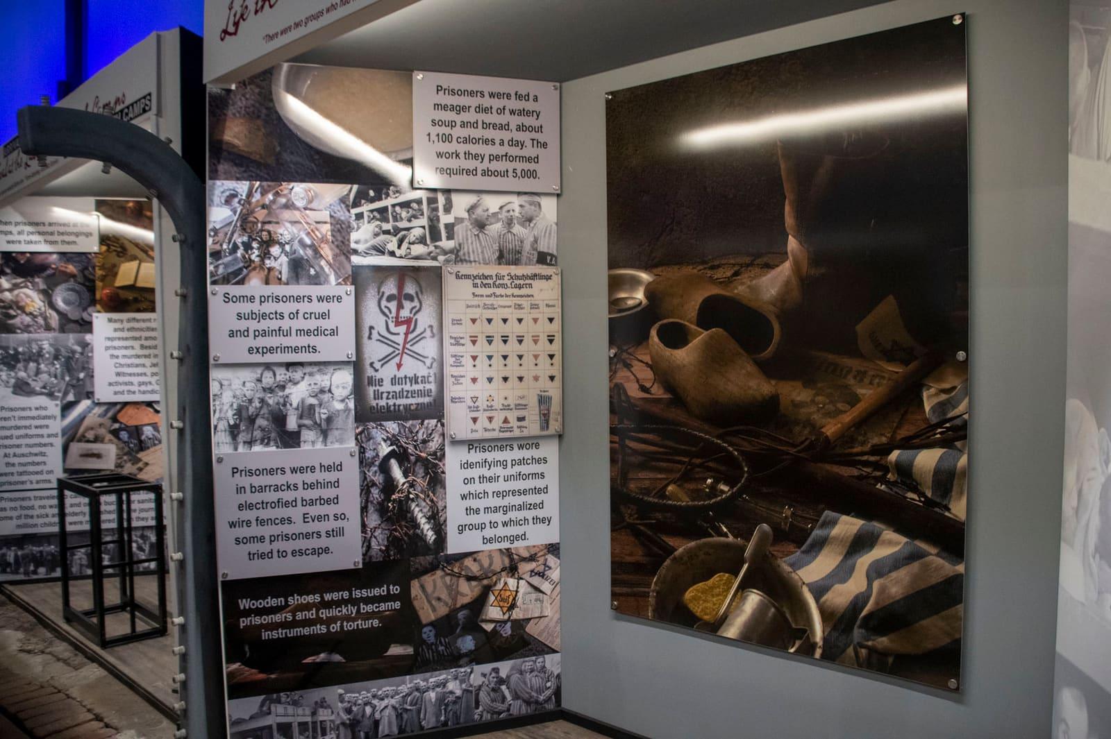Exhibit panels with historical photographs and text flank a glass case containing a suitcase and clothing.