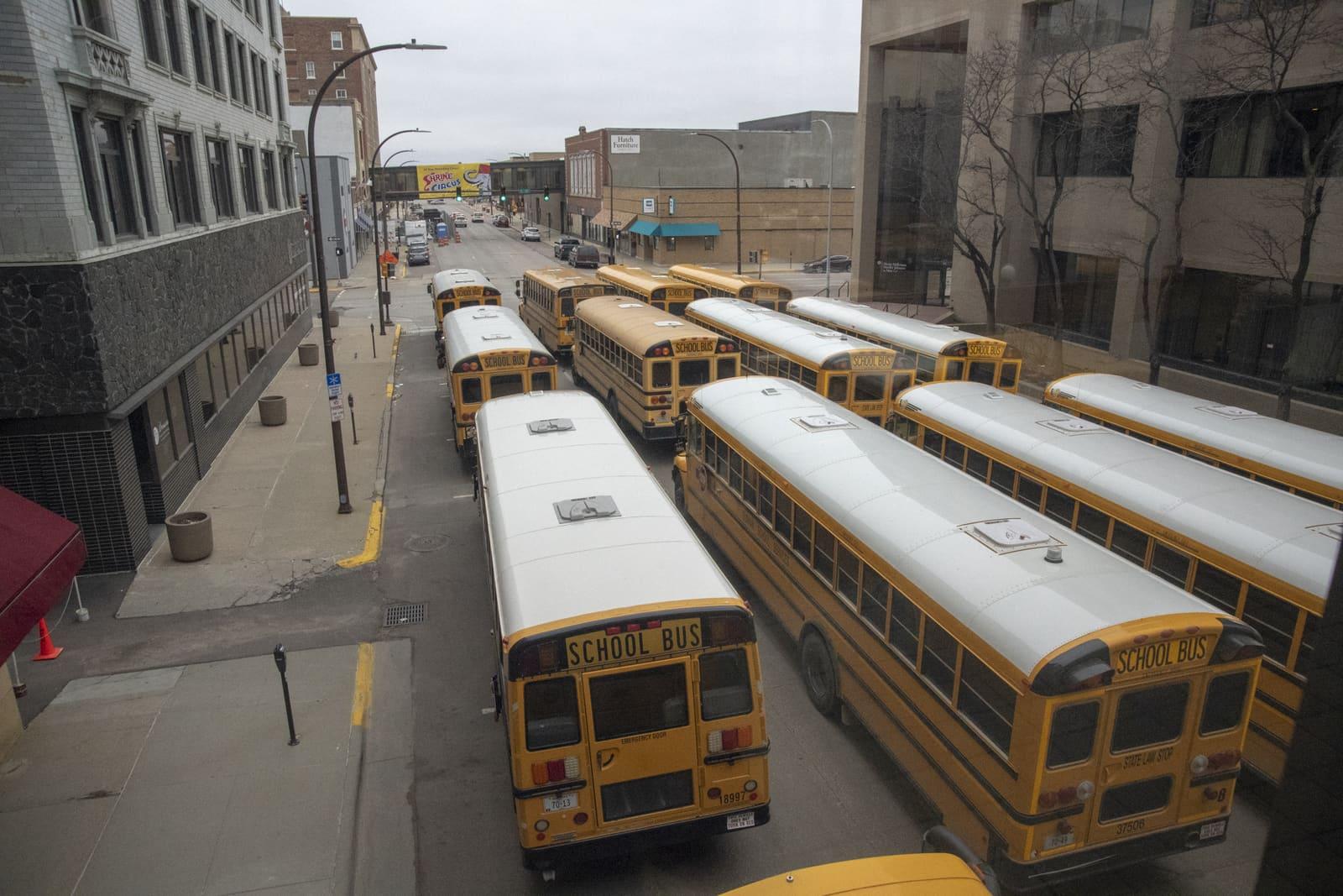 Rows of school buses fill a downtown street.
