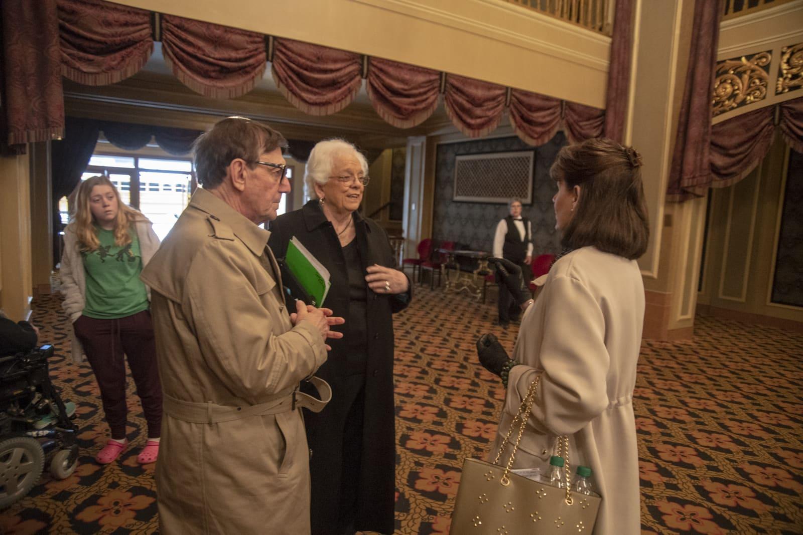 Several adults converse in an ornate lobby.