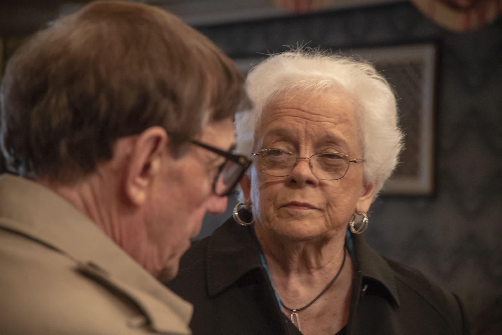 An adult listens as an adult speaks in the foreground.