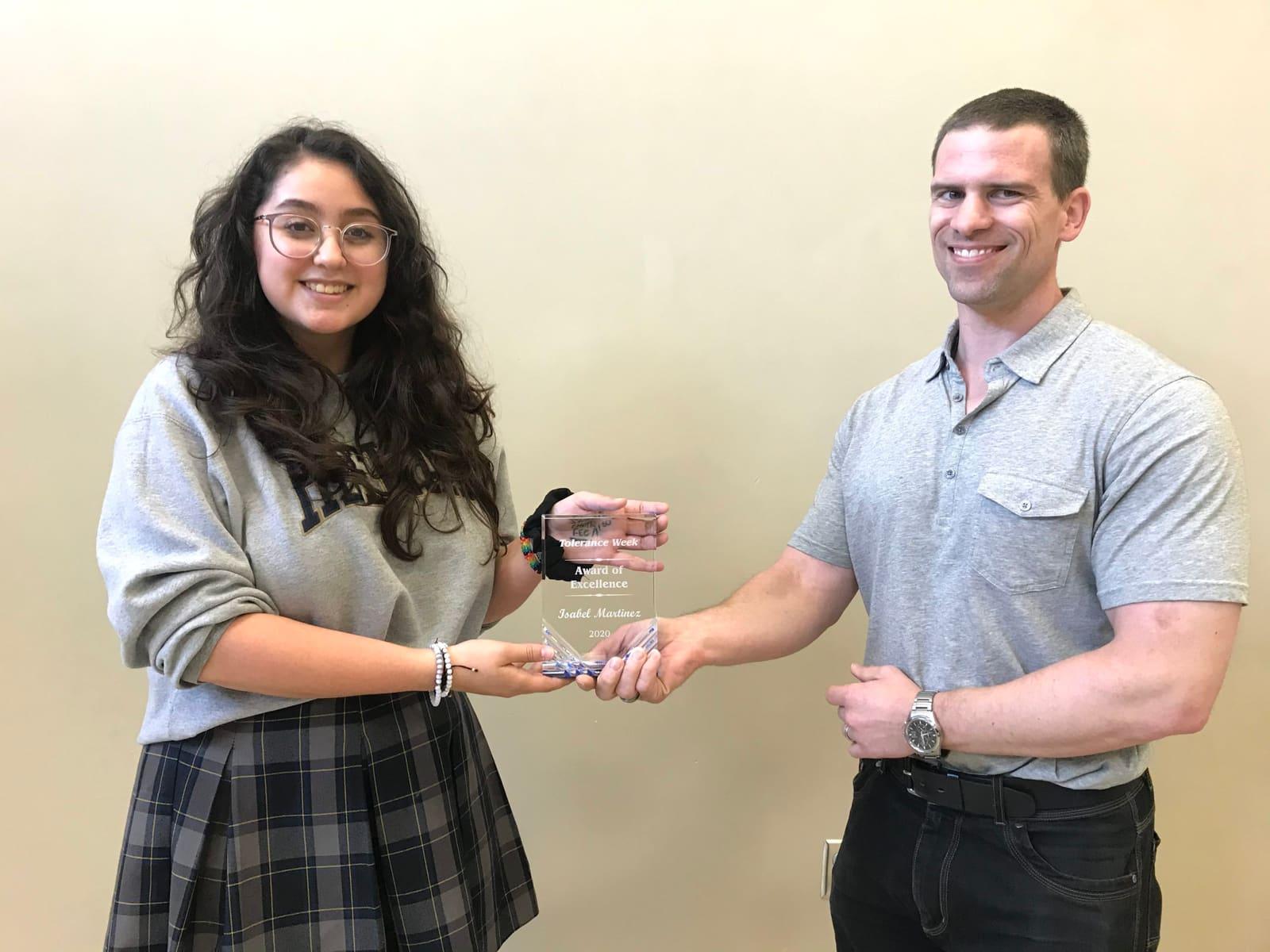 A student receives a small clear plaque from an adult.