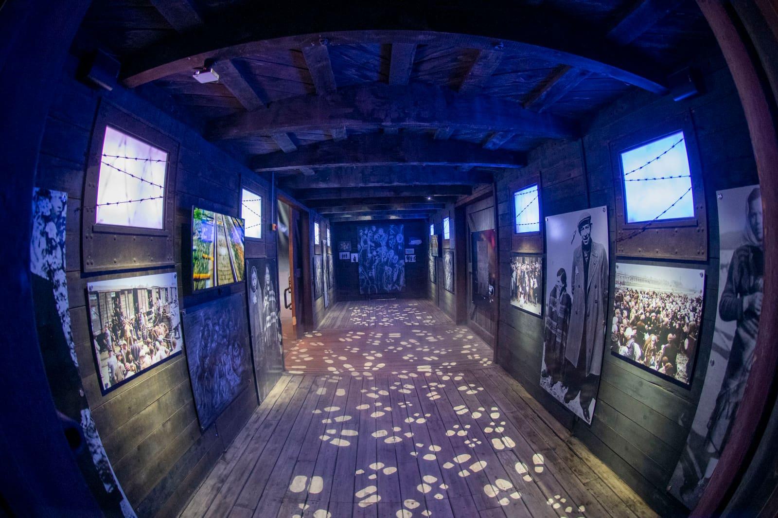 A long blue-lit corridor has historic displays and projected footprints.