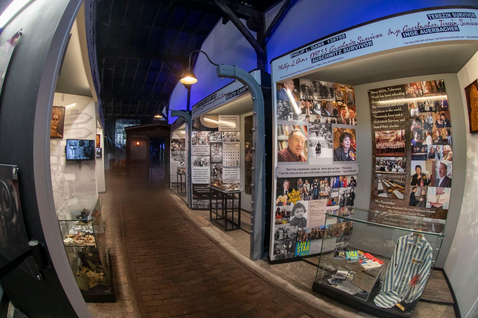 A narrow exhibit corridor passes panels, artifacts, and a metal cart.