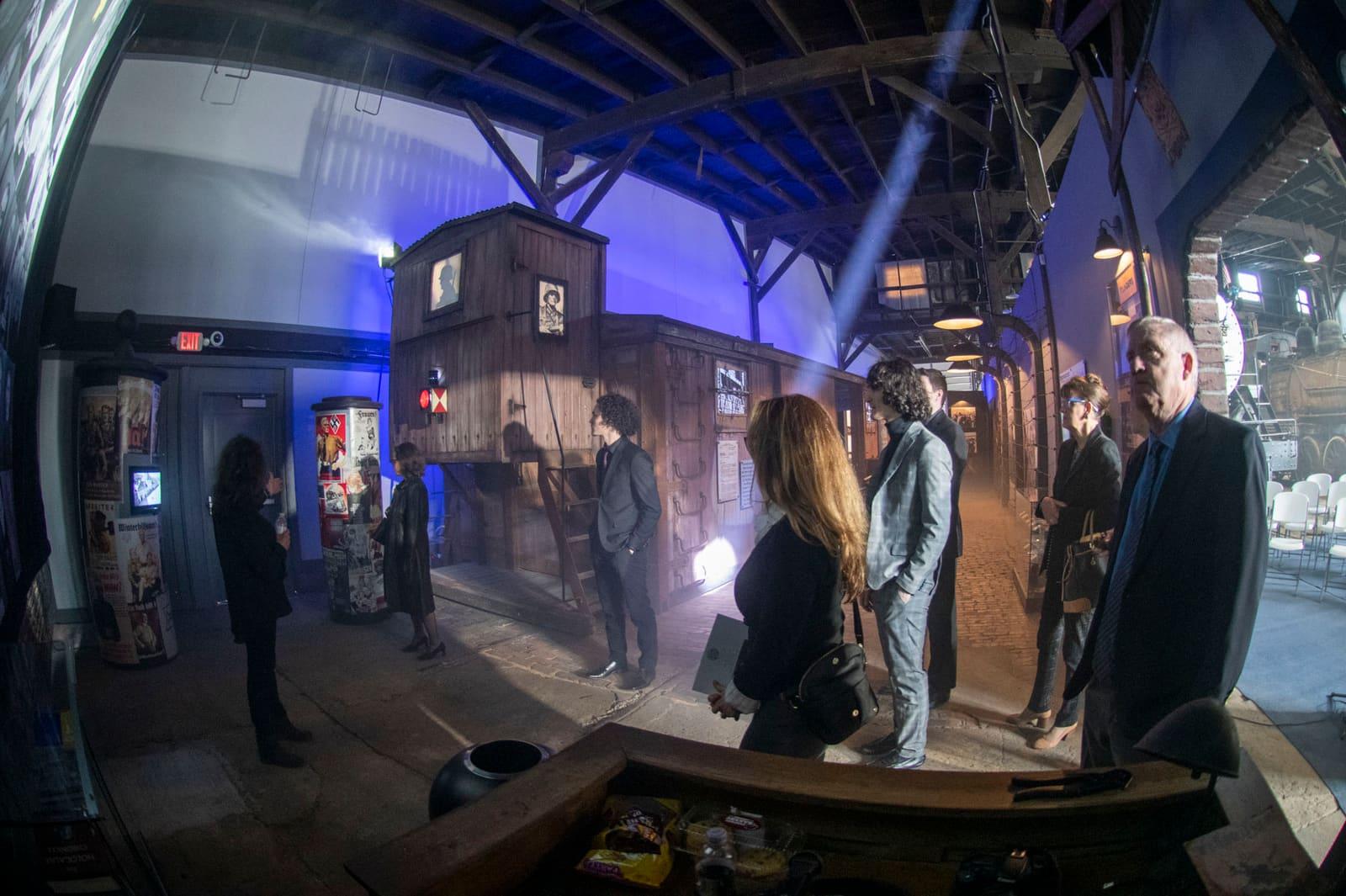 Visitors gather beside a wooden railcar wall inside an exhibit.