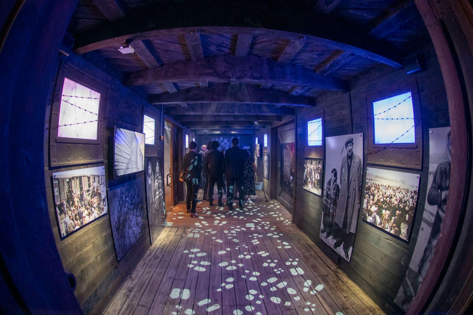 Visitors walk through a long blue-lit exhibit corridor.