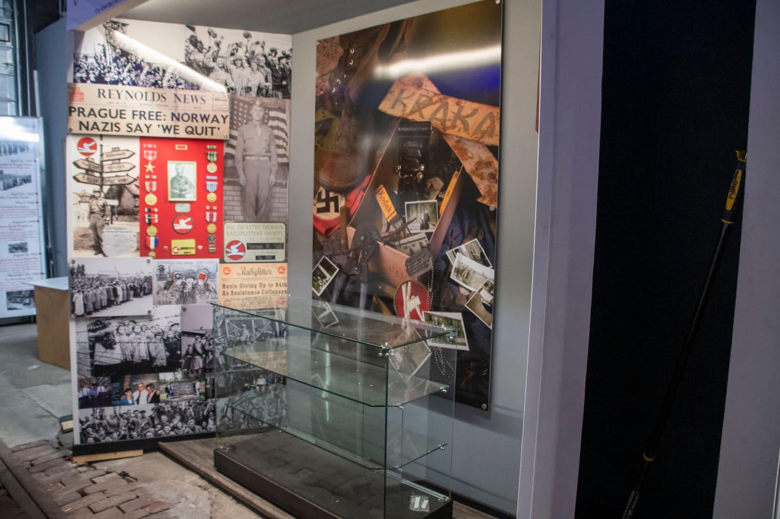 A glass case displays documents and an illustrated poster.