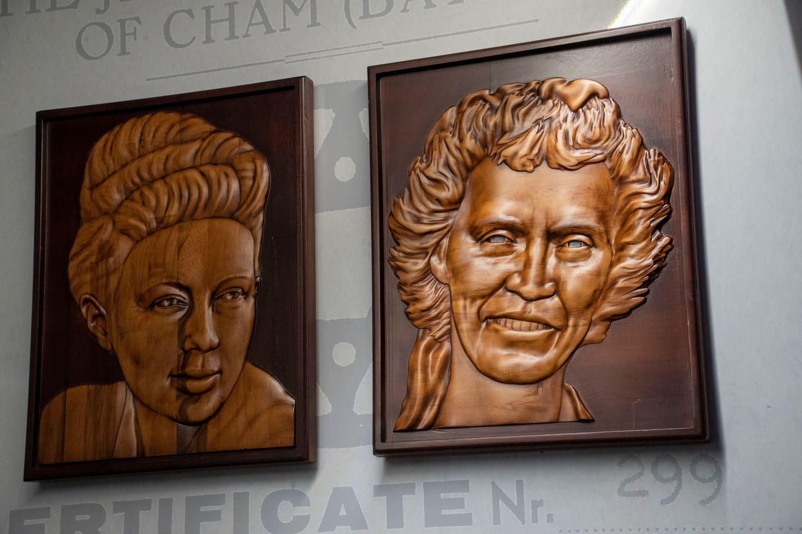 Two carved wooden portrait reliefs hang side by side.