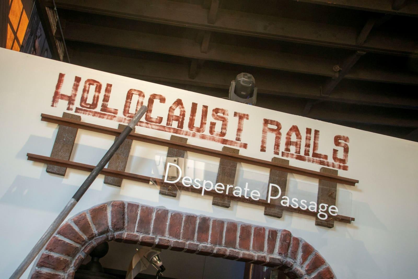 A sign above a brick arch reads “Holocaust Rails: Desperate Passage.”