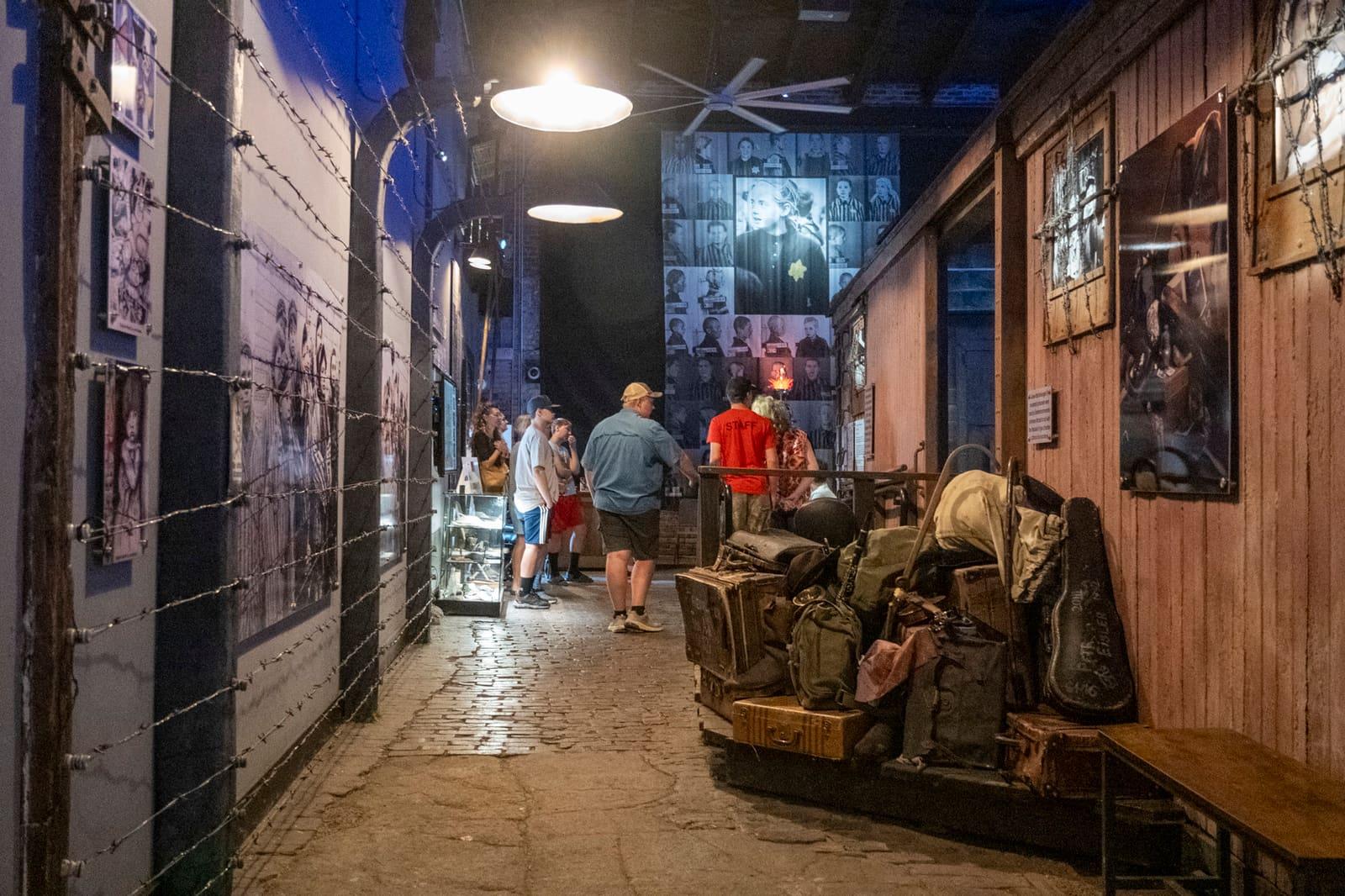 Visitors walk through a narrow wood-paneled exhibit corridor.