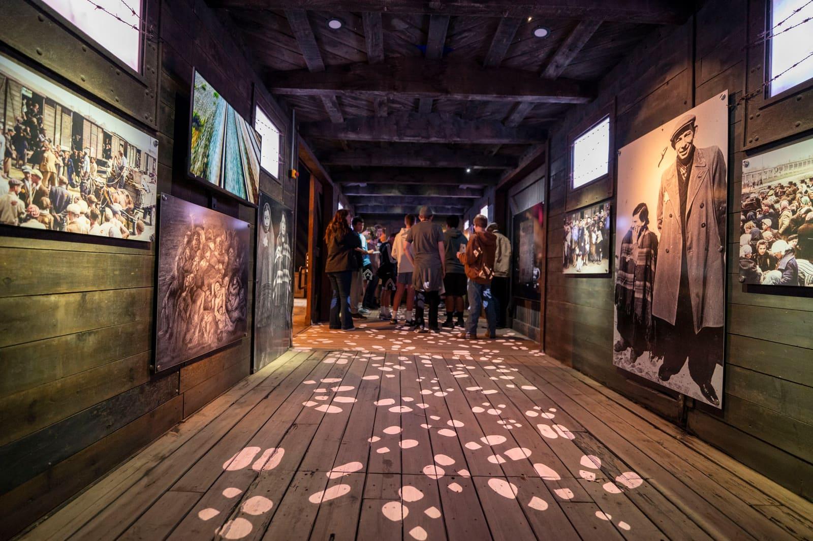 Visitors walk along a corridor patterned with projected footprints.