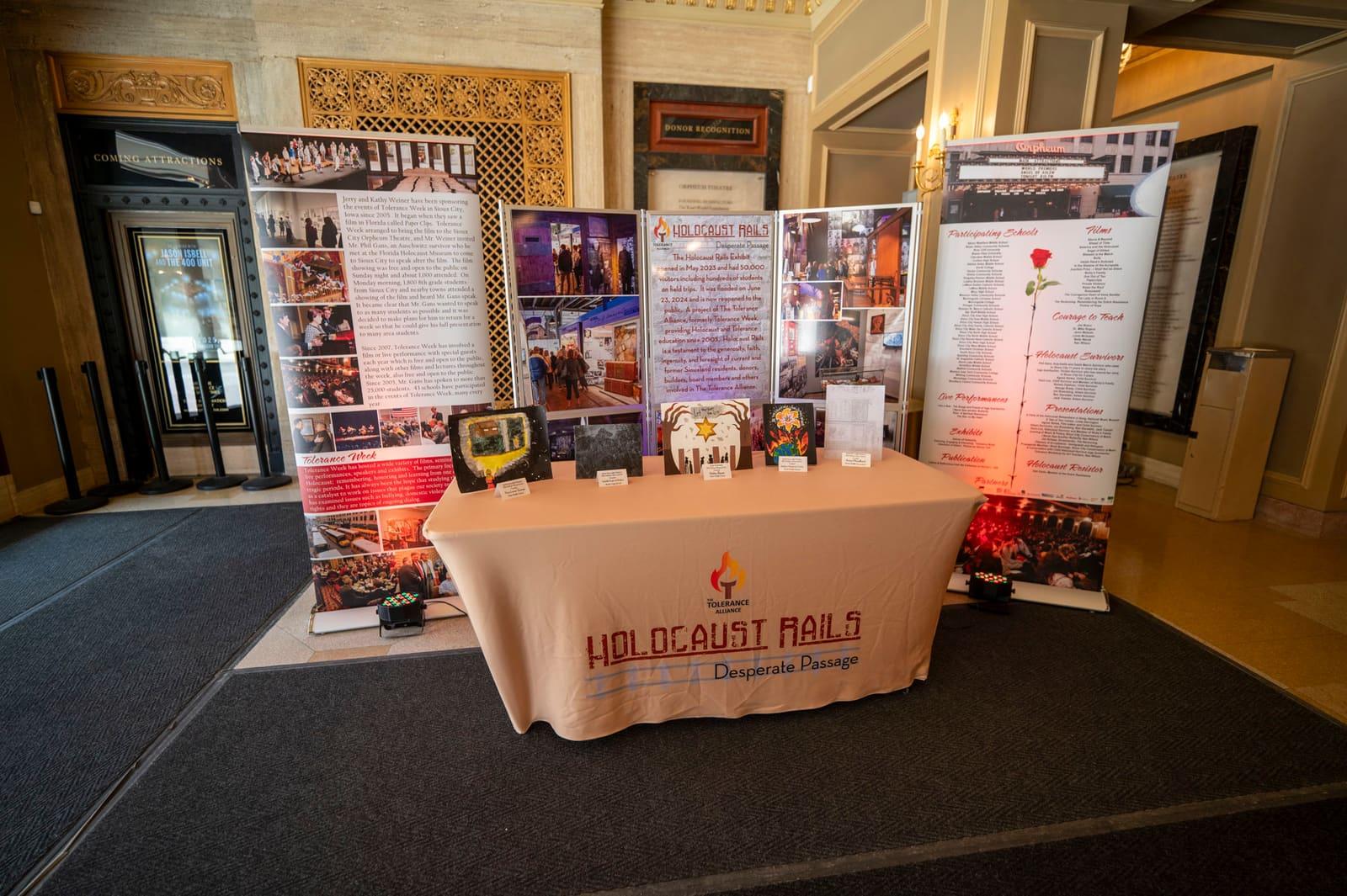 A table display stands between tall Holocaust Rails banners.