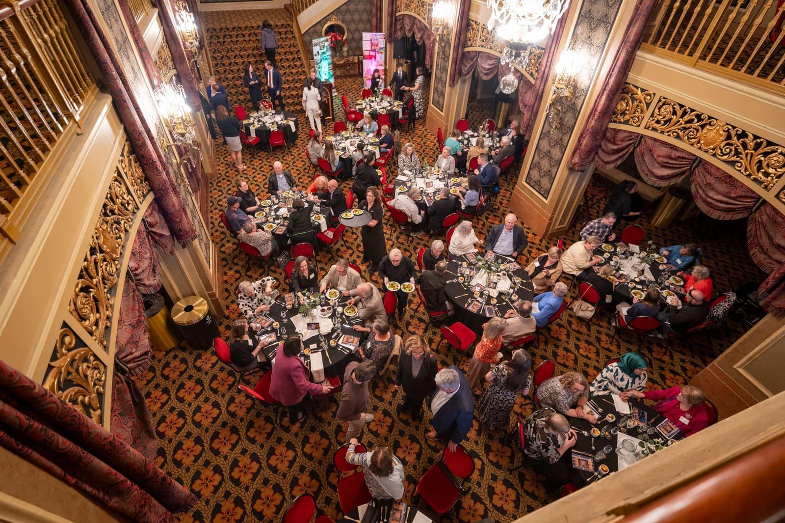 An overhead view shows guests filling round banquet tables.