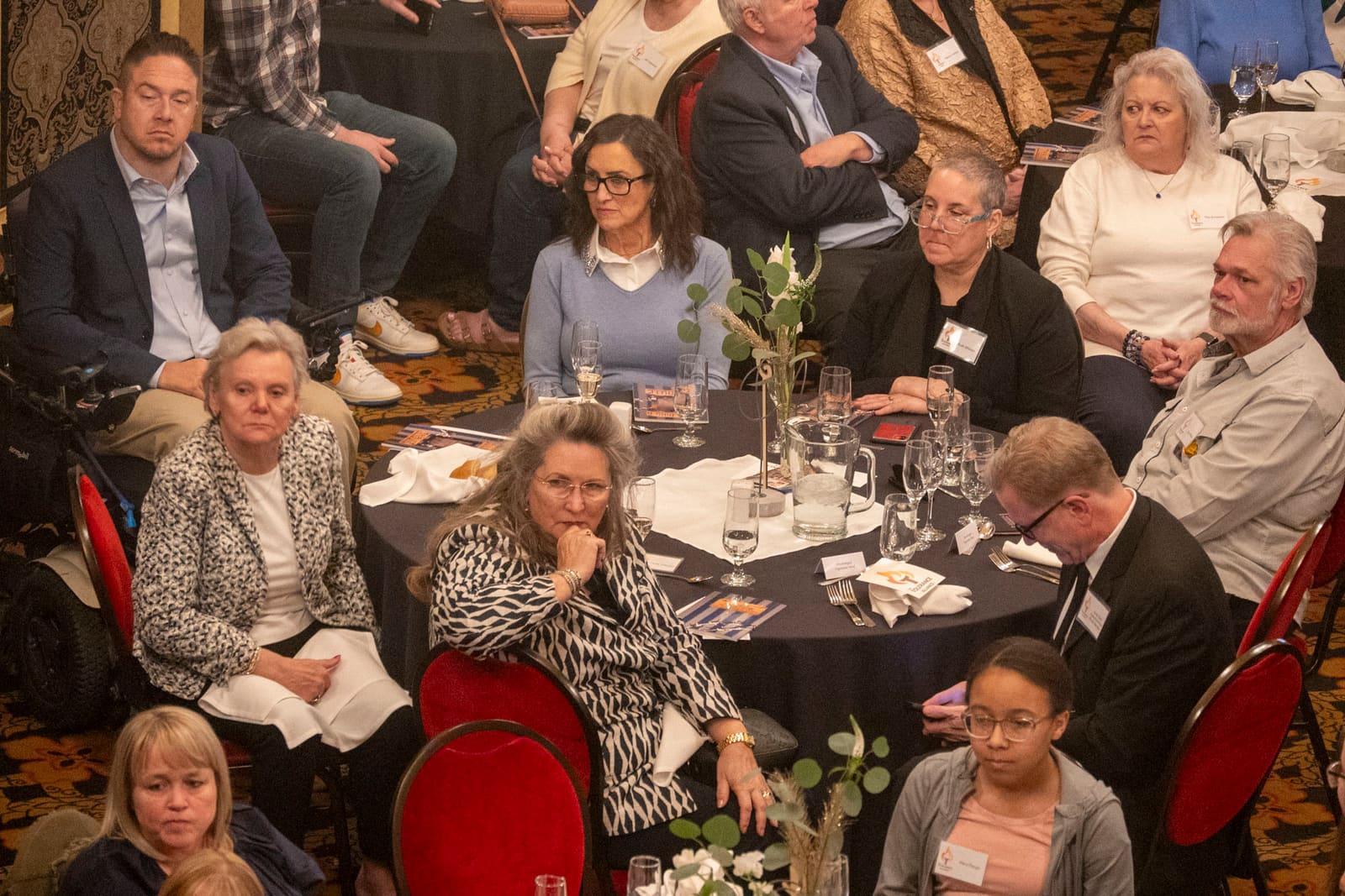 Banquet attendees sit around crowded round tables.