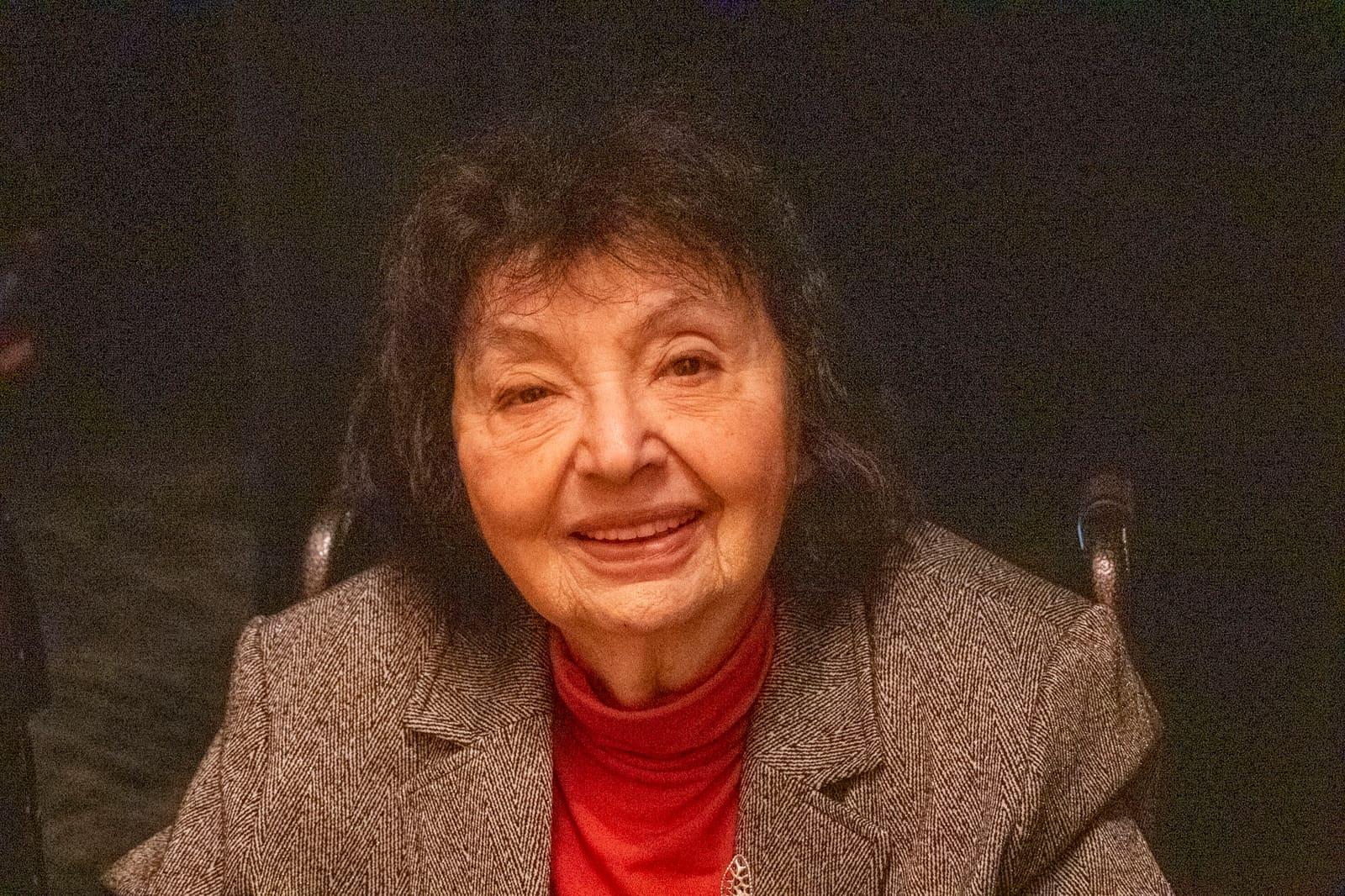 Close-up portrait of an adult in a gray jacket and red shirt.