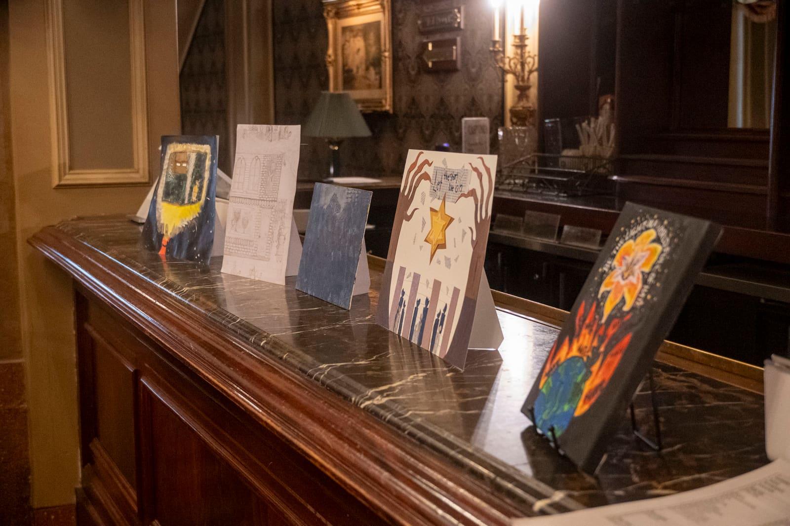 Student artworks are propped along a wooden counter.