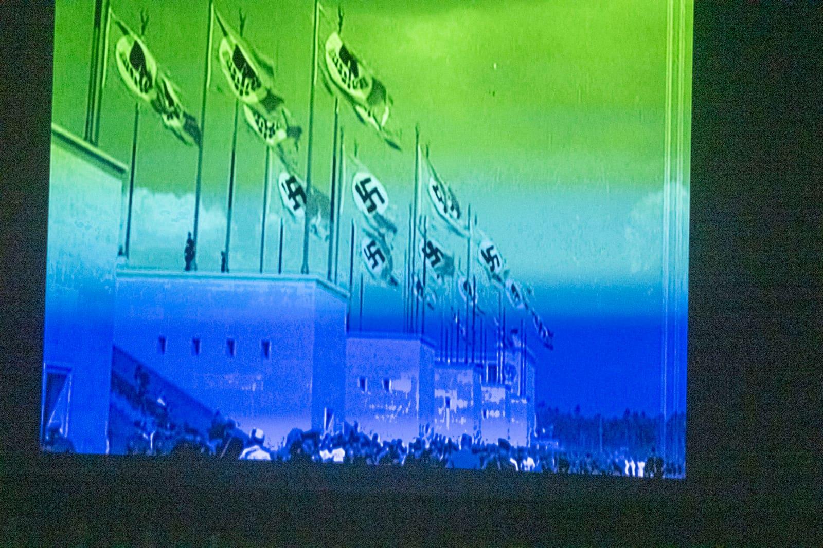 A projected color-tinted image shows flags above a large building.