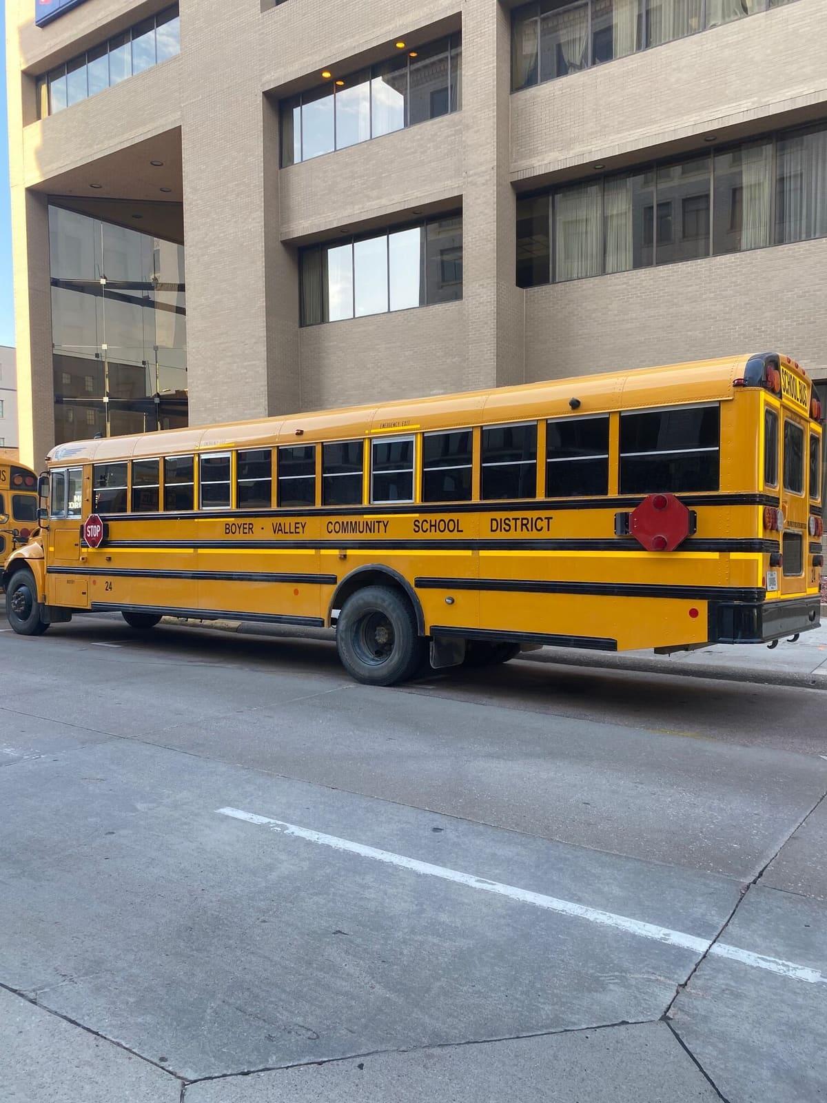 A yellow school bus is parked beside a concrete building.